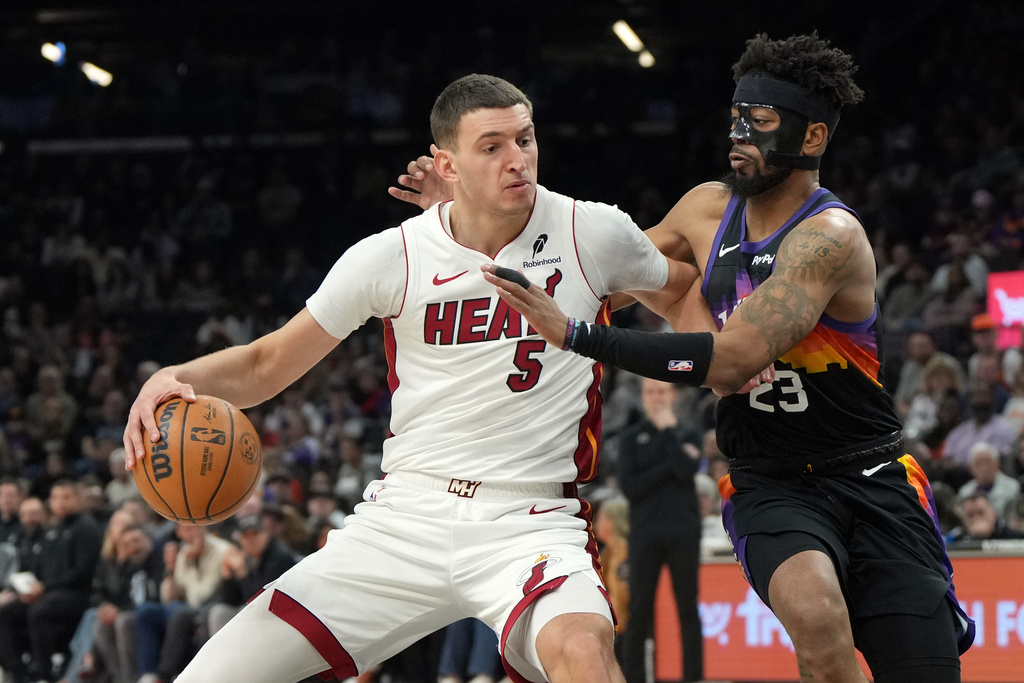 Miami Heat forward Nikola Jovic (5) shields the ball from Phoenix Suns guard Jordan Goodwin (23) during the first half of an NBA basketball game, Sunday, Jan. 25, 2026, in Phoenix. (AP Photo/Rick Scuteri)