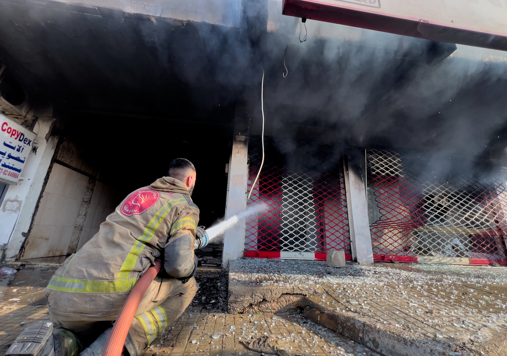 A firefighter extinguishes a burned shop at a building that was hit by an Israeli airstrike in Dahiyeh, a southern suburb of Beirut, Lebanon, Tuesday, March 3, 2026. (AP Photo/Hussein Malla)