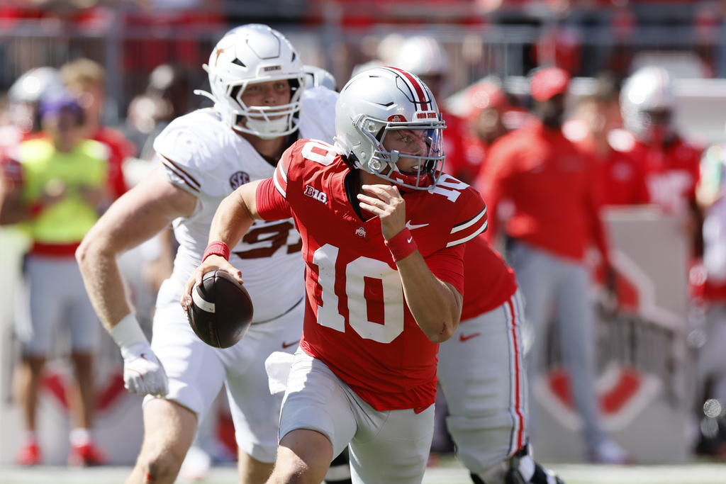 Ohio State quarterback Julian Sayin is chased out of the pocket by Texas defensive lineman Ethan Burke during the second half of an NCAA college football game, Saturday, Aug. 30, 2025, in Columbus, Ohio. (AP Photo/Jay LaPrete)