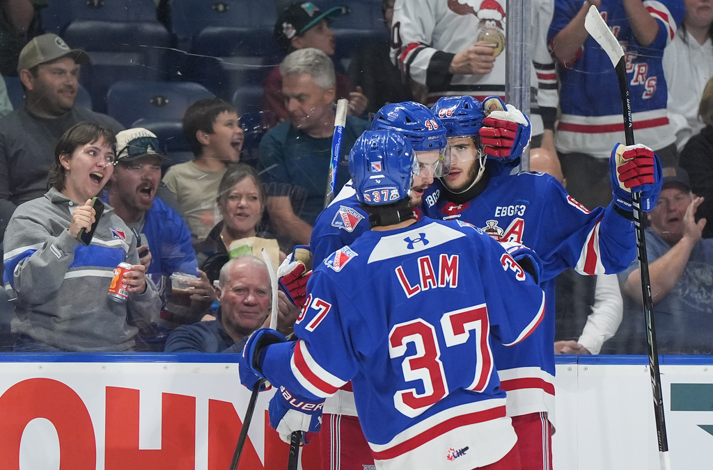 Kitchener Rangers' Luca Romano, back right, Christian Humphreys and Tanner Lam celebrate Romano's goal during the second period of a Memorial Cup hockey game against the Chicoutimi Sagueneens, in Kelowna, B.C., on Tuesday, May 26, 2026. (Darryl Dyck/The Canadian Press via AP)