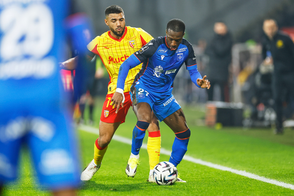 Auxerre's Lamine Sy, right, challenges for the ball with Lens' Matthieu Udol during the French League One soccer match between Lens and Auxerre in Lens, France, Saturday, Jan. 17, 2026. (AP Photo/Jean-Francois Badias)