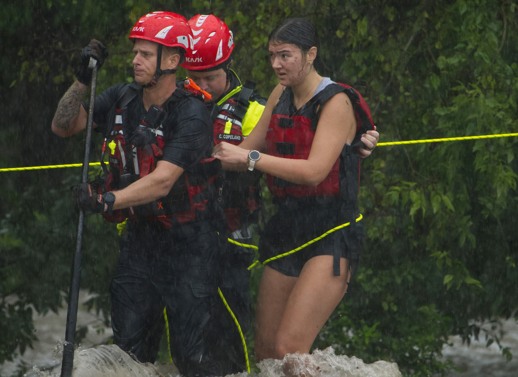 Members of the Boerne Fire Dept. rescue a woman from flood waters on Wednesday, July 15, 2026, in Boerne, Texas. (AP Photo/Darren Abate)
