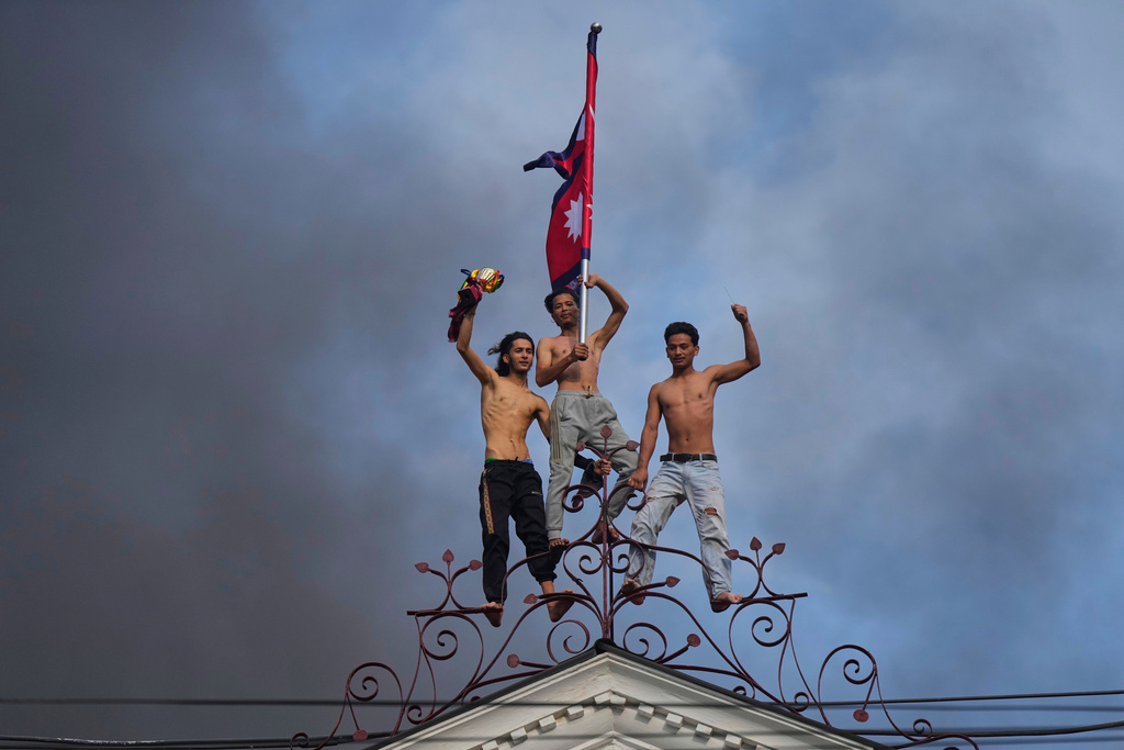 Protesters celebrate standing at the top of the Singha Durbar, the seat of Nepal's government's various ministries and offices, after it was set on fire during a protest against social media ban and corruption in Kathmandu, Nepal, Tuesday, Sept. 9, 2025. (AP Photo/Niranjan Shrestha, File)