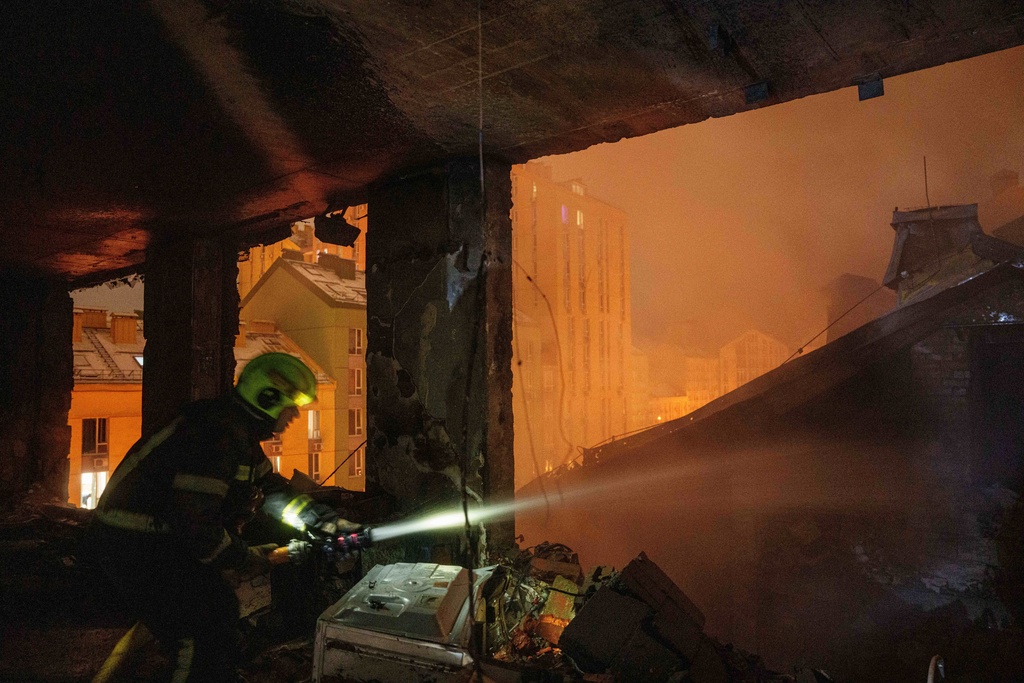 A rescue worker put out fire of a residential building damaged by a Russian strike on Kyiv, Ukraine, on Friday, Jan. 9, 2026. (AP Photo/Evgeniy Maloletka)
