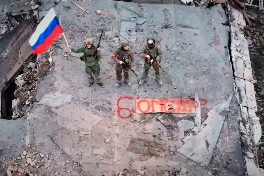 In this image made from video, provided by Russian Defense Ministry Press Service on Thursday, Dec. 11, 2025, Russian soldiers hold a Russian national flag in Siversk, a city in the Donetsk region, Ukraine. (Russian Defense Ministry Press Service via AP)