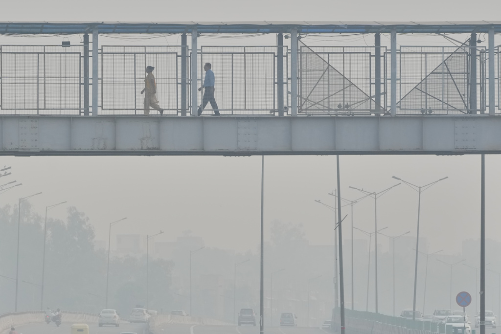 FILE - People walk through an overhead bridge amidst morning smog in New Delhi, India, Oct. 21, 2025. (AP Photo/Manish Swarup, File)