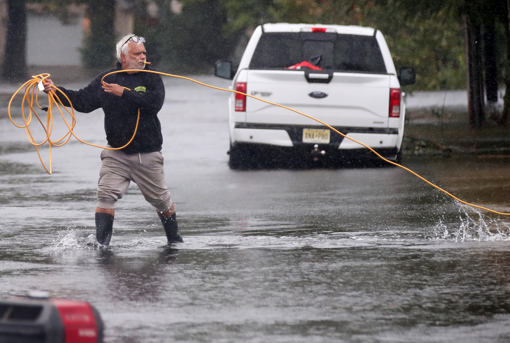 Jose Rosario pulls an extension cord out of his flooded garage to connect to a generator on Catherine St. Saturday, Sept. 26, 2026, in Long Branch, N.J. (AP Photo/Noah K. Murray)