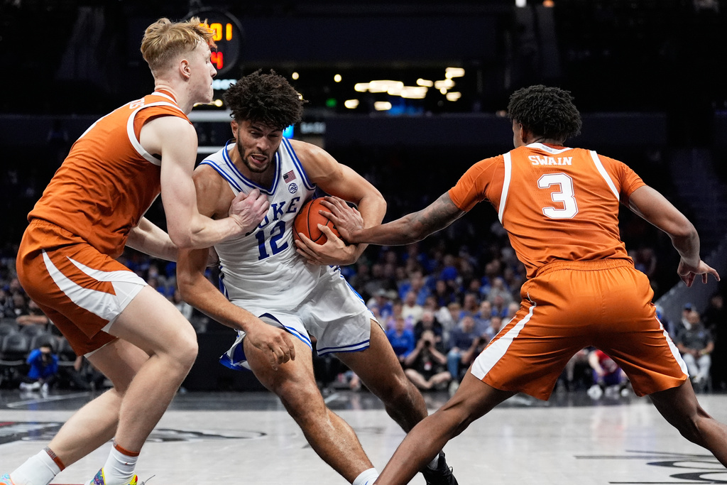 Duke forward Cameron Boozer drives to the basket between Texas center Matas Vokietaitis, left, and forward Dailyn Swain during the second half of an NCAA college basketball game, Tuesday, Nov. 4, 2025, in Charlotte, N.C. (AP Photo/Chris Carlson)