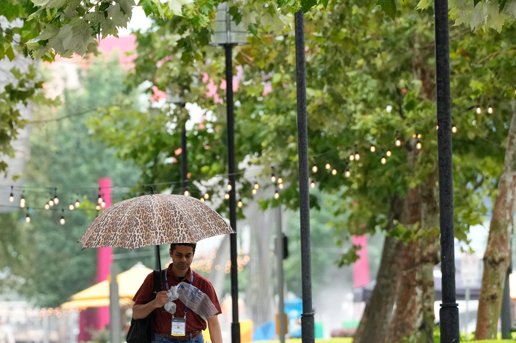 A convention attendee walk through the rain outside the George R. Brown Convention Center, Wednesday, June 17, 2026, in Houston. (AP Photo/Kevin M. Cox)