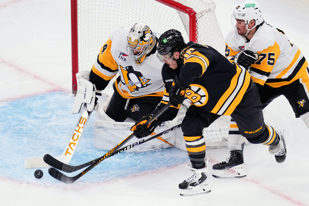 Pittsburgh Penguins goaltender Stuart Skinner, left, makes a save on a shot by Boston Bruins right wing David Pastrnak, center, during the third period of an NHL hockey game, Tuesday, March 3, 2026, in Boston. (AP Photo/Charles Krupa)