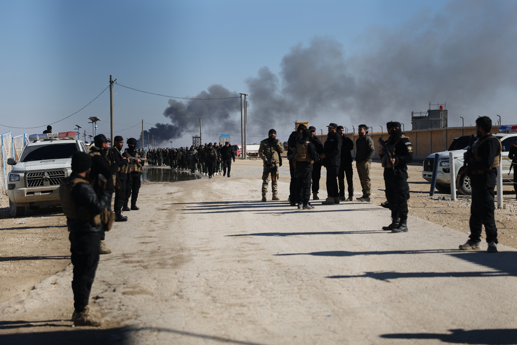 Syrian government forces patrol inside the al-Hol camp as smoke rises from an arms depot explosion in northeastern Syria's Hasakeh province, Syria, Wednesday, Jan. 21, 2026, after the withdrawal of the Syrian Democratic Forces (SDF). (AP Photo/Ghaith Alsayed)