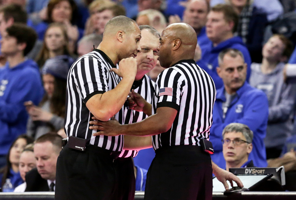 FILE - NCAA officials Matt Potter, left, Tim Clougherty, center, and Jeffrey Anderson, right, confer to decide whether Seton Hall's Angel Delgado committed a flagrant foul during the second half of an NCAA college basketball game against Creighton in Omaha, Neb., Jan. 17, 2018. (AP Photo/Nati Harnik, File)