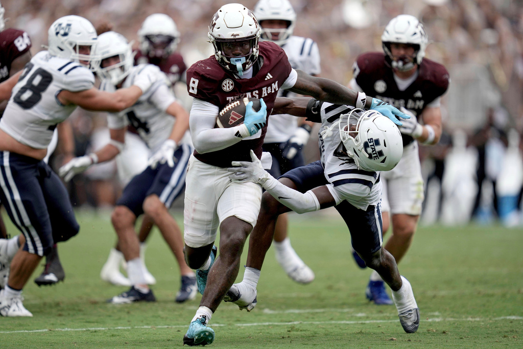 Texas A&M running back Le'Veon Moss (8) fends off Utah State cornerback Courage Ugo (22) on his way to the end zone for a touchdown during the second quarter of an NCAA college football game Saturday, Sept. 6, 2025, in College Station, Texas. (AP Photo/Sam Craft)