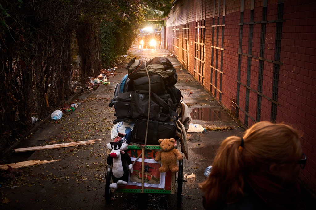 A migrant's belongings are packed before he leaves as police in the background prepares to carry out eviction orders at an abandoned school building where hundreds of mostly undocumented migrants had been living, in Badalona, near Barcelona, Spain, Wednesday, Dec. 17, 2025. (AP Photo/Emilio Morenatti)