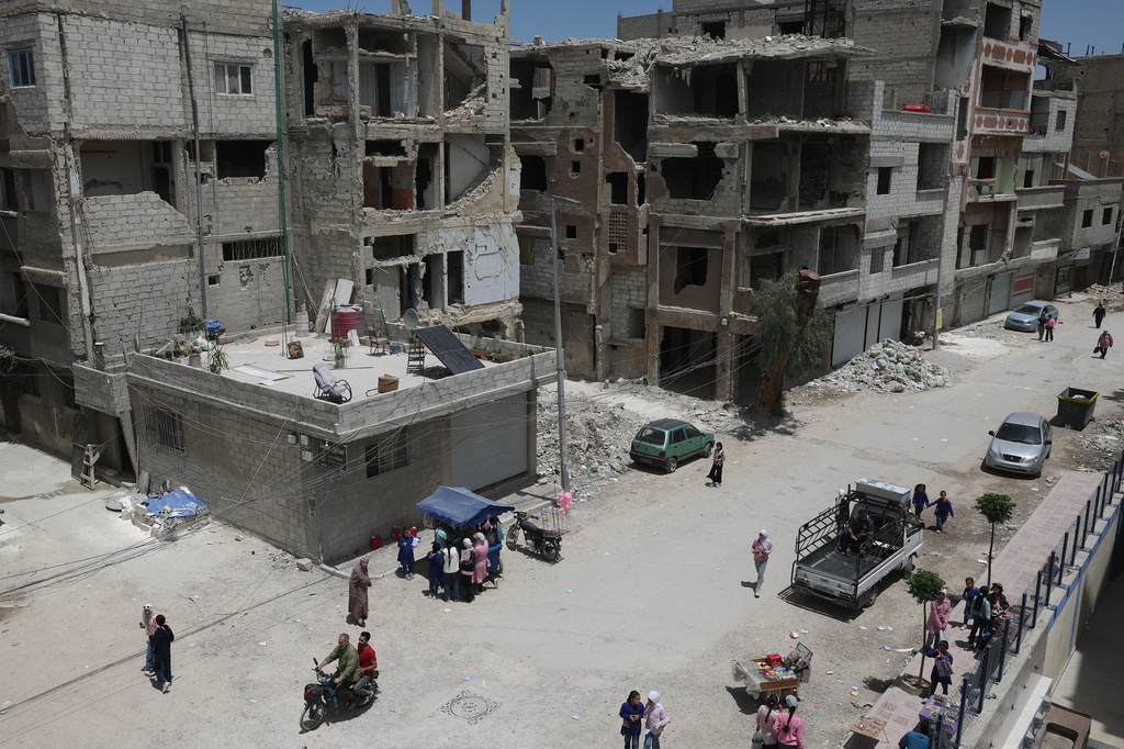 Daily life continues among damaged buildings, some under reconstruction, in the Yarmouk Palestinian refugee camp, devastated by years of fighting and displacement during the Syrian war, in Damascus, Syria, Tuesday, May 19, 2026. (AP Photo/Ghaith Alsayed)