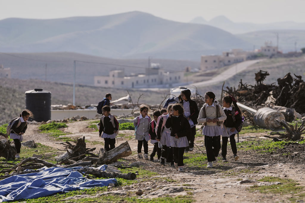Palestinian students walk to school using an alternative route that is nearly twice as long because a fence separates their village from the nearby Israeli settlement of Carmel, near the West Bank village of Umm al-Khair, Tuesday, April 14, 2026. (AP Photo/Mahmoud Illean)