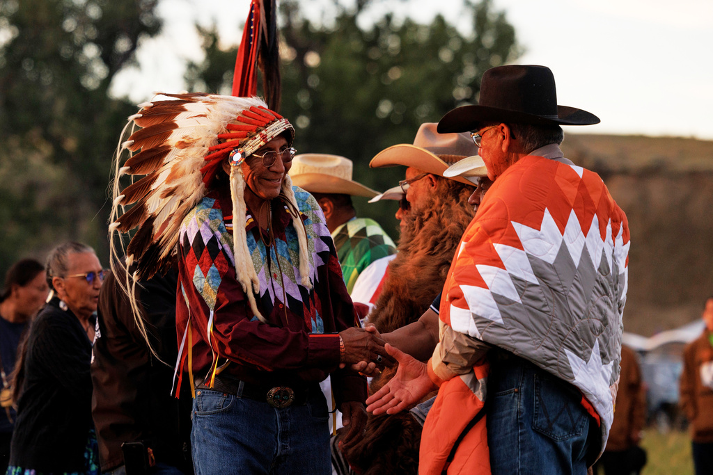 Campers shake hands before the horse ceremony during festivities to commemorate the 150th anniversary of the Battle of the Little Bighorn, Wednesday, June 24, 2026, in Crow Agency, Mont. (AP Photo/Tailyr Irvine)