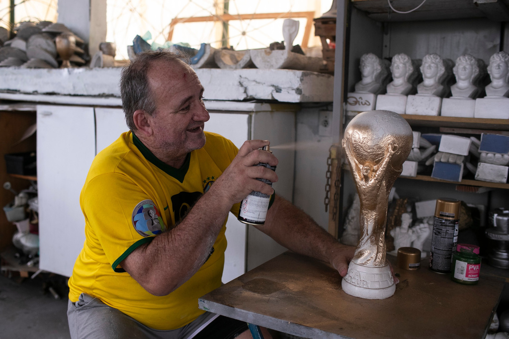 Jarbas Meneghini Carlini sprays a FIFA World Cup trophy replica he made, at his home in Rio de Janeiro, Friday, May 15, 2026. (AP Photo/Bruna Prado)