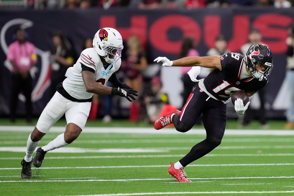 Houston Texans wide receiver Xavier Hutchinson (19) runs past Arizona Cardinals cornerback Will Johnson during the first half of an NFL football game Sunday, Dec. 14, 2025, in Houston. (AP Photo/Ashley Landis)