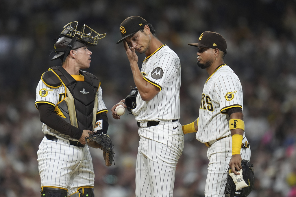 San Diego Padres starting pitcher Yu Darvish wipes his face as meets on the mound with catcher Freddy Fermin, left, and first baseman Luis Arraez during the fifth inning of a baseball game against the Baltimore Orioles Tuesday, Sept. 2, 2025, in San Diego. (AP Photo/Gregory Bull)
