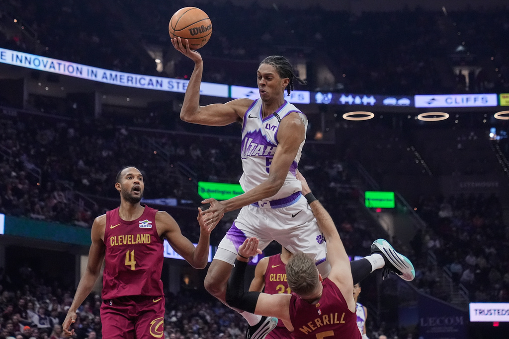 Utah Jazz forward Cody Williams, center, is called for an offensive foul on Cleveland Cavaliers guard Sam Merrill, bottom, as center Evan Mobley (4) looks on in the first half of an NBA basketball game in Cleveland, Monday, Jan. 12, 2026. (AP Photo/Sue Ogrocki)