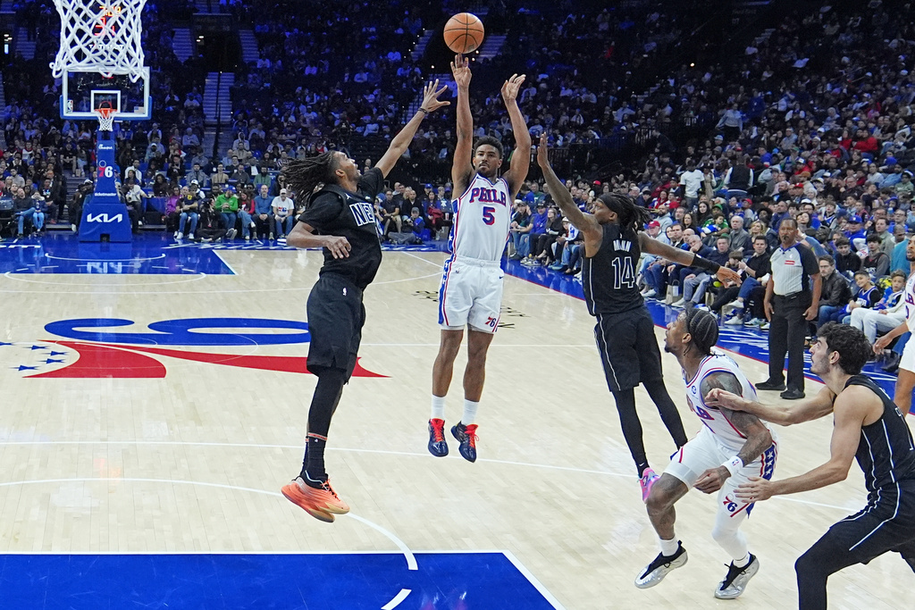 Philadelphia 76ers' Quentin Grimes (5) shotos between Brooklyn Nets' Ziaire Williams, and Terance Mann (14) during the first half of an NBA basketball game Saturday, March 14, 2026, in Philadelphia. (AP Photo/Matt Rourke)