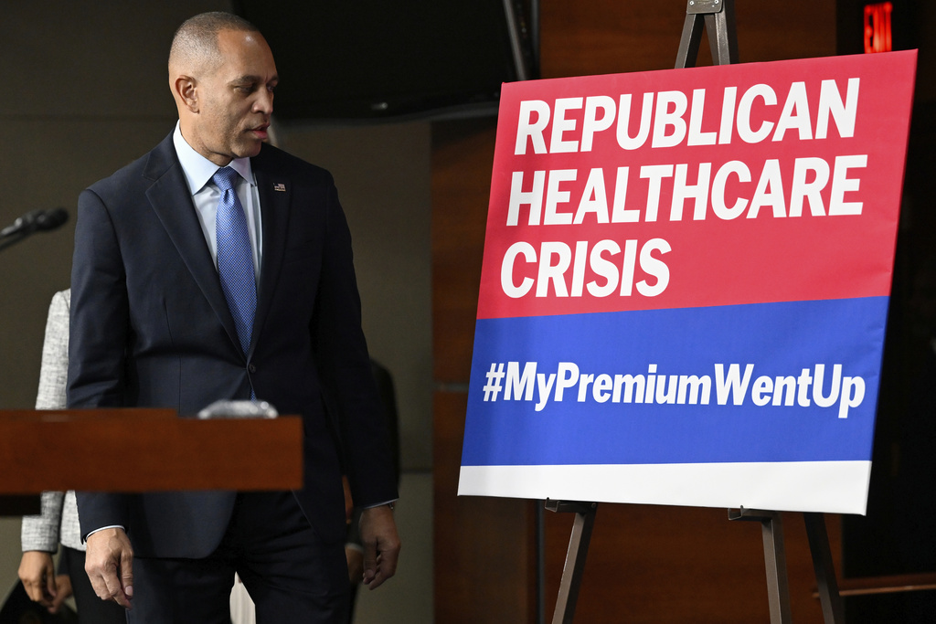 House Minority Leader Hakeem Jeffries, D-N.Y., passes a sign on a stage that the House Democratic leaders held a news conference on the 8th day of government shutdown at the U.S. Capitol on Wednesday, Oct. 8, 2025, in Washington. (AP Photo/John McDonnell)
