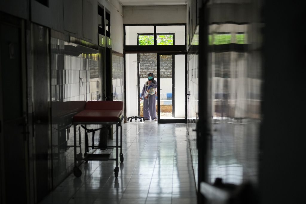 A mother carries her son at an isolation ward for measles patients, at Moh Anwar Hospital in Sumenep on Madura Island, Indonesia, Wednesday, Sept. 10, 2025. (AP Photo/Dita Alangkara)