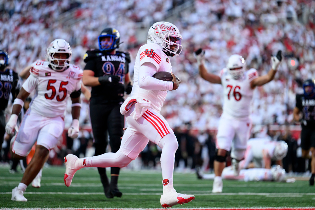 Utah quarterback Devon Dampier, center, runs the ball for a touchdown during the first half of an NCAA college football game against Kansas, Saturday, Oct. 10, 2026, in Salt Lake City. (AP Photo/Tyler Tate)
