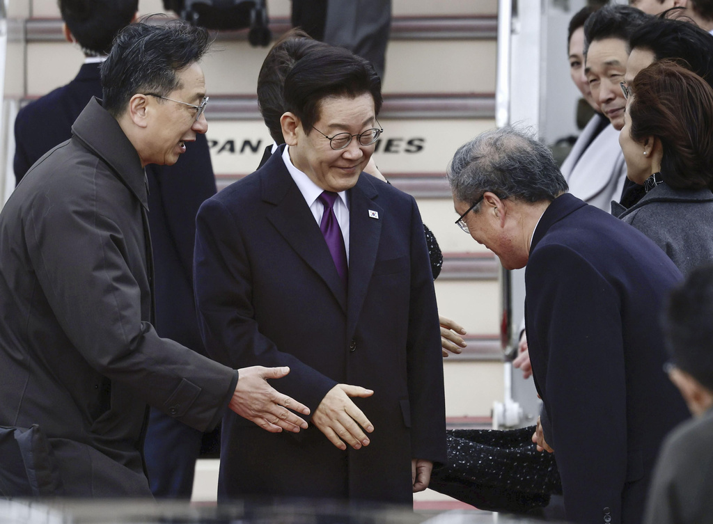 South Korean President Lee Jae Myung, center, is greeted on his arrival at Kansai International Airport in Izumisano city, Osaka, western Japan, Tuesday, Jan. 13, 2026. (Kyodo News via AP)