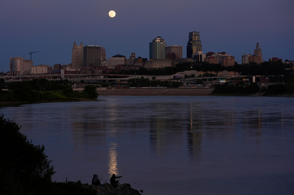 FILE - People fish in the Kansas River as the full moon rises beyond the downtown skyline, May 11, 2025, in Kansas City, Mo. (AP Photo/Charlie Riedel, file)