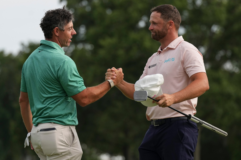 Rory McIlroy, of Northern Ireland, speaks with Wyndham Clark as Clark wins the final round of the BMW Championship golf tournament, Sunday, Aug. 23, 2026, in St. Louis. (AP Photo/Jeff Roberson)