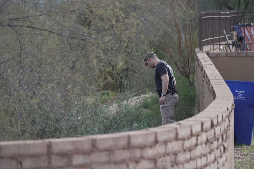 An investigator walks around homes in the neighborhood where Annie Guthrie, whose mother Nancy Guthrie has been missing for more than a week, lives just outside Tucson, Ariz., on Tuesday, Feb. 10, 2026. (AP Photo/Ty ONeil)