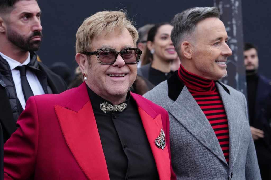 Elton John, center, and David Furnish, right, depart the Valentino Spring/Summer 2026 Haute Couture collection presented in Paris, Wednesday, Jan. 28, 2026. (AP Photo/Aurelien Morissard)