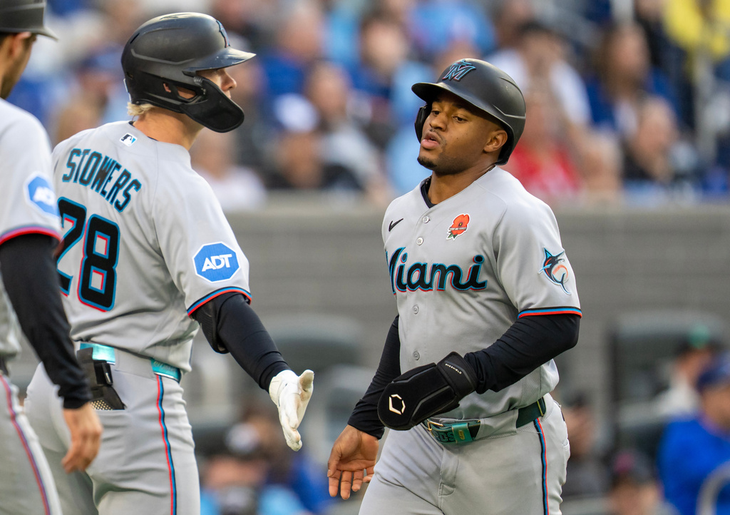 Miami Marlins' Xavier Edwards, right, is congratulated by Kyle Stowers (28) after scoring against the Toronto Blue Jays during first-inning baseball game action in Toronto, Monday May 25, 2026. (Frank Gunn/The Canadian Press via AP)