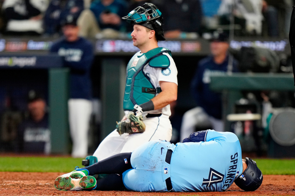 Toronto Blue Jays outfielder George Springer (4) rolls on the ground after taking a pitch to the knee from Seattle Mariners pitcher Bryan Woo (22) during seventh inning MLB Game 5 of baseball's American League Championship Series action in Seattle, Friday, Oct. 17, 2025. (Frank Gunn/The Canadian Press via AP)