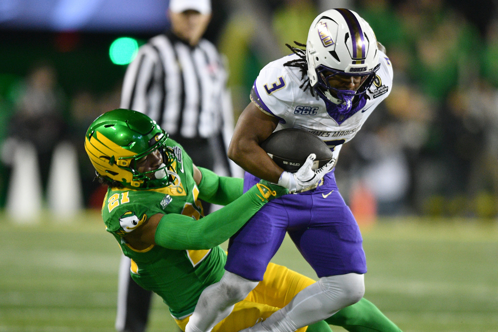 Oregon defensive back Aaron Flowers (21) tackles James Madison running back Wayne Knight (3) during the first half in the first round of the NCAA College Football Playoff, Saturday, Dec. 20, 2025, in Eugene, Ore. (AP Photo/Mark Ylen)