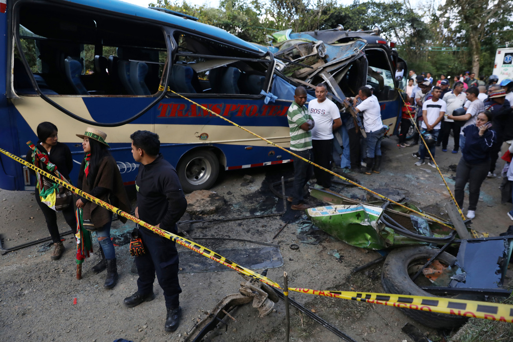 People gather around a bus hit by an explosive device on the Pan-American Highway in Cajibio, Colombia, Saturday, April 25, 2026, after an attack blamed by authorities on dissident groups of the former FARC rebels killed at least a dozen people. (AP Photo/Santiago Saldarriaga)