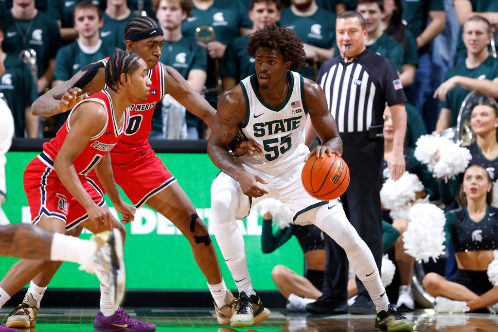 Michigan State forward Coen Carr (55) maneuvers against Detroit Mercy guards Lance Stone, left, and Nate Johnson, center, during the first half of an NCAA college basketball game, Friday, Nov. 21, 2025, in East Lansing, Mich. (AP Photo/Al Goldis)