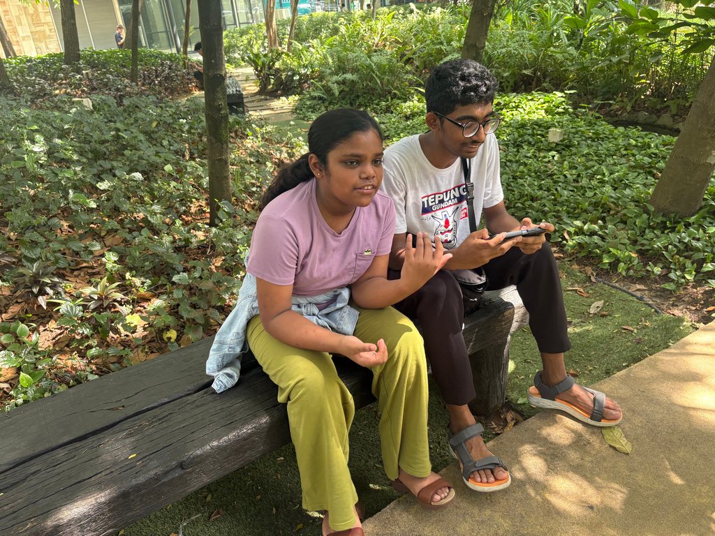 Siblings Saaradha Saravanan, 12, left, and Aadhavan Saravanan, 15, sit in a park in Petaling Jaya, near Kuala Lumpur Malaysia Monday, June 1, 2026. (AP Photo/Eileen Ng)