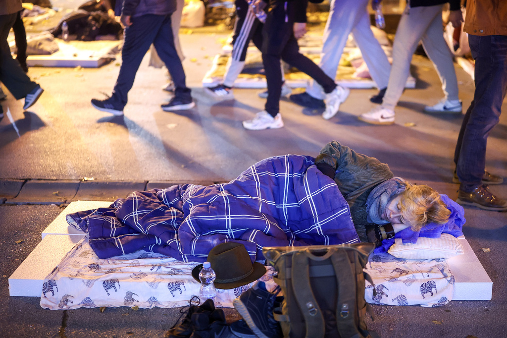 A person sleeps on a street while taking a break on their march to Novi Sad for a rally on Nov. 1 marking the first anniversary of a train station disaster that killed 16 people, in Indjija, Serbia, Thursday, Oct. 30, 2025. (AP Photo/Armin Durgut)