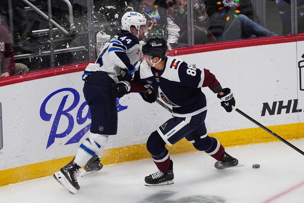 Colorado Avalanche center Martin Necas, right, checks Winnipeg Jets defenseman Josh Morrissey, left, in the first period of an NHL hockey game Friday, Dec. 19, 2025, in Denver. (AP Photo/David Zalubowski)