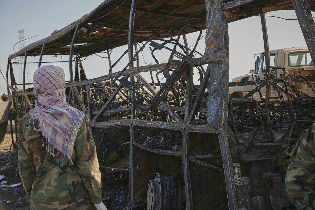 A man looks at a burned-out bus that collided with a truck and a motorbike Tuesday evening, causing a massive fire and killing at least 70 people, including children, most of them Afghans returning from Iran, in western Herat province, Afghanistan, Wednesday, Aug. 20, 2025. (AP Photo/Omid Haqjoo)