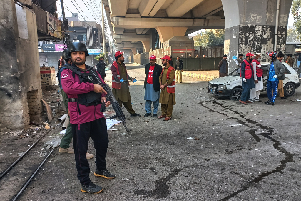 Security officials and rescue workers gather at the site of a suicide bombing at the main gate of headquarters of the Federal Constabulary (FC) in Peshawar, Pakistan, Monday, Nov. 24, 2025. (AP Photo/Muhammad Zubair)