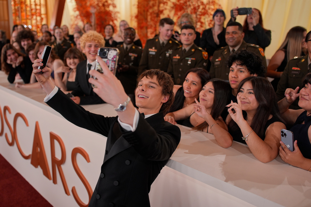 Mason Thames takes selfies with guests as he arrives at the Oscars on Sunday, March 15, 2026, at the Dolby Theatre in Los Angeles. (AP Photo/John Locher)