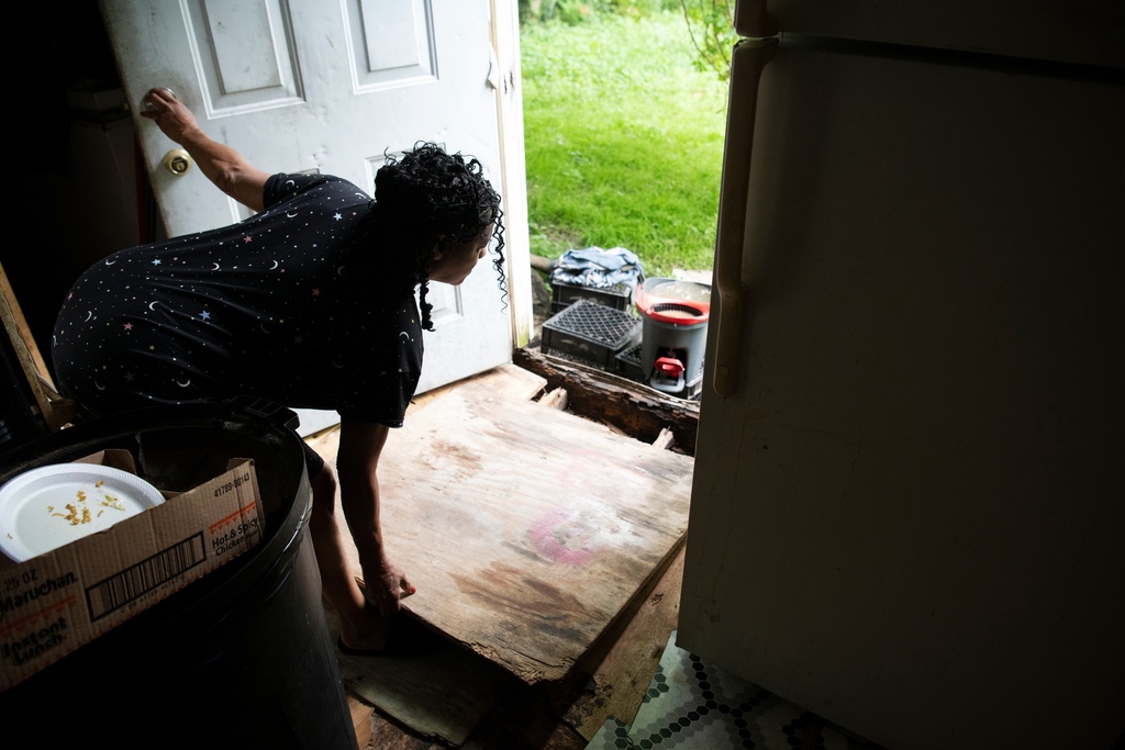 Sandra Byrd moves a board to show water damage to her home in Cahokia Heights, Ill., May 20, 2025. (AP Photo/Michael Phillis)