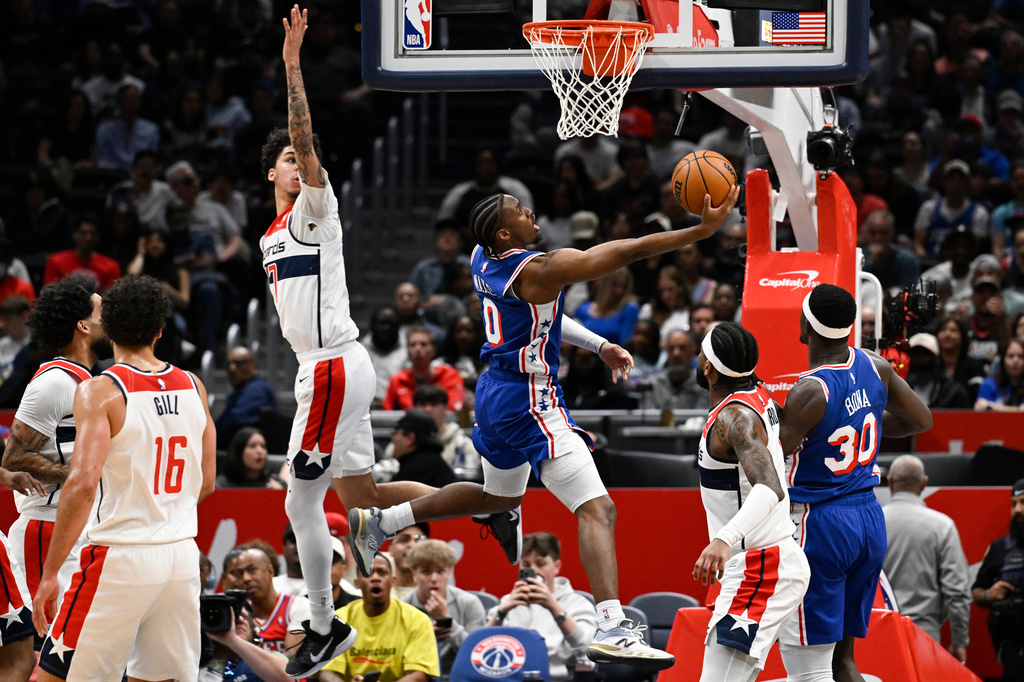 Philadelphia 76ers guard Tyrese Maxey (0) goes to shoot past Washington Wizards guard Will Riley during the first half of an NBA basketball game, Wednesday, April 1, 2026, in Washington. (AP Photo/John McDonnell)