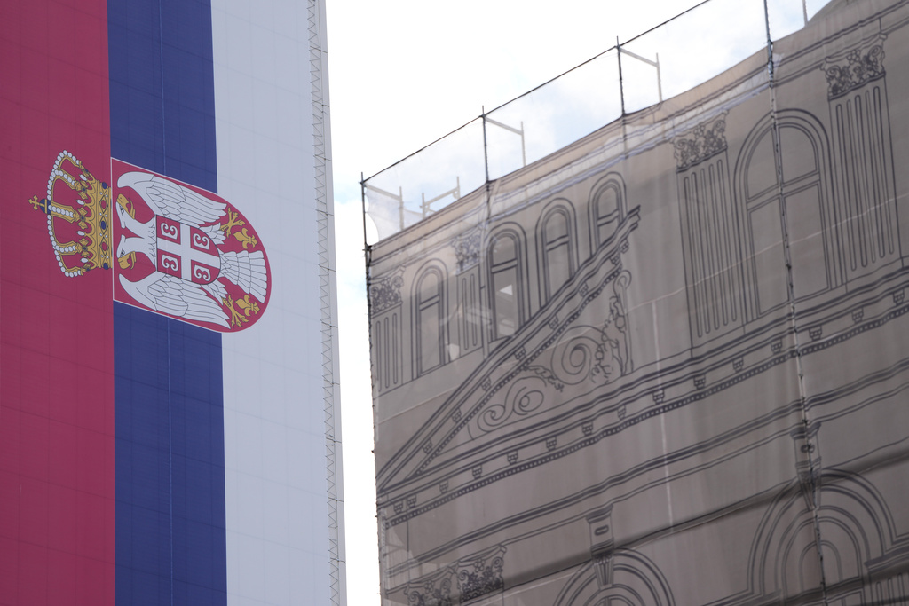 A giant Serbian flag is seen on a building near former Yugoslav army headquarters destroyed in a U.S.-led NATO bombing campaign in 1999, right, in Belgrade, Serbia, Tuesday, Nov. 4, 2025. (AP Photo/Darko Vojinovic)