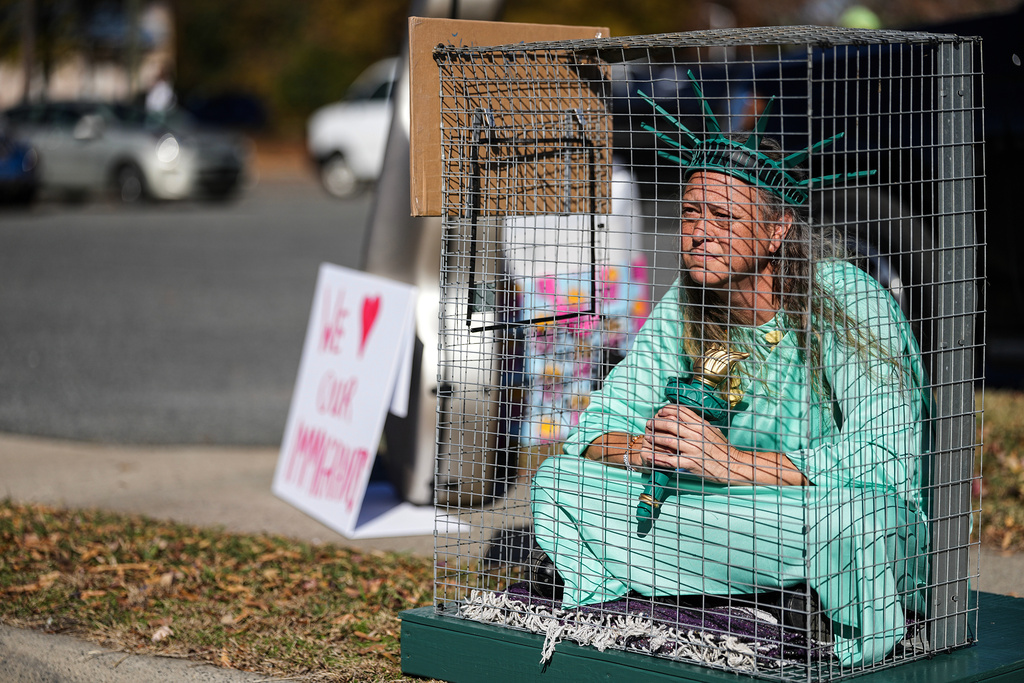Shana Blake sits in a cage dressed as the Statue of Liberty to protest federal law enforcement presence in Charlotte, N.C. Monday, Nov. 17, 2025. (AP Photo/Matt Kelley)
