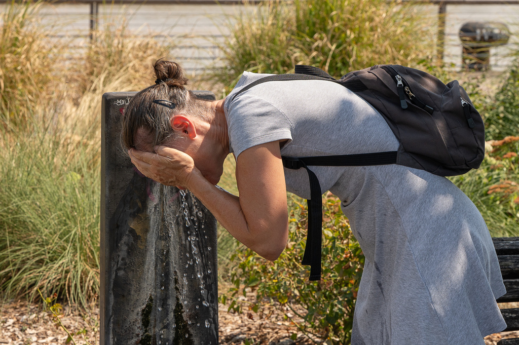 A woman splashes water on her face at a public fountain on a hot day in Bordeaux, France, Thursday, Aug. 13, 2026, as a heatwave affects much of the country. (AP Photo/Caroline Blumberg)